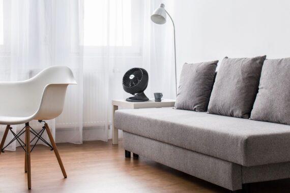 Lifestyle of a 560B medium air circulator sitting on a side table by a couch in a modern living room
