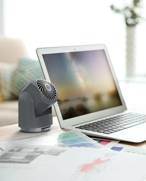 Lifestyle of a Storm Gray Flippi v6 personal air circulator on a desk next to an open laptop