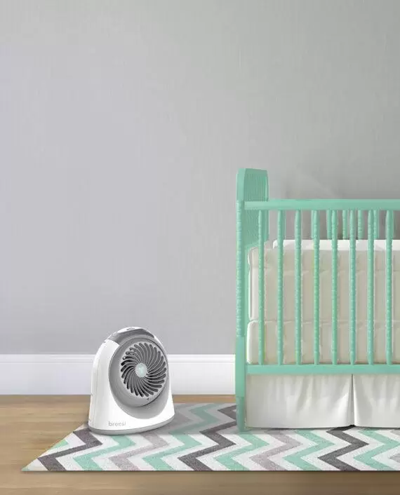 Lifestyle of a White Breesi LS Medium Nursery Air Circulator by a teal crib