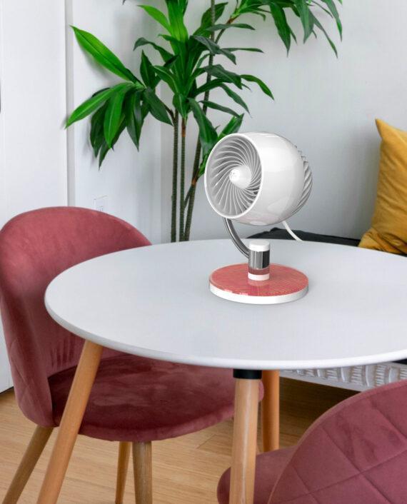 Pivot3U Compact Air Circulator on a small white table with a dark pink chair and green plant in the background