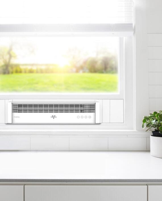 White Vornado Portal Lifestyle image. Portal mounted in the window of a kitchen with a plant, countertop, and surrounding wall visible.