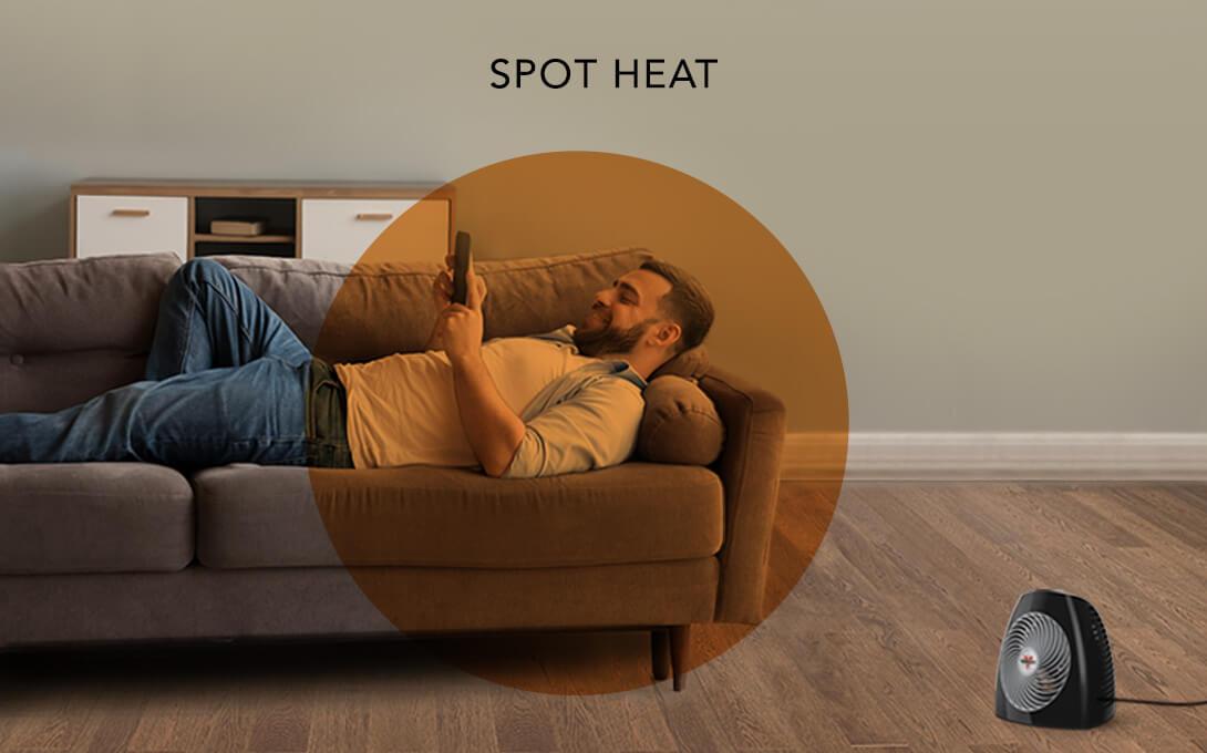 Man laying on a couch with the MVH heater on the floor. There is an orange circle overlay on him to indicate a spot heat space.